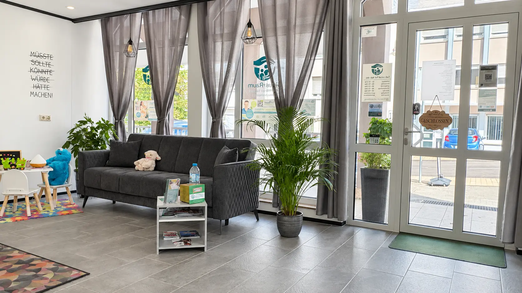Familienfreundlicher Wartebereich mit Sofa und Kindertisch